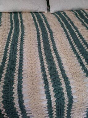 Handmade crochet blanket features a striped pattern in teal and cream. This item